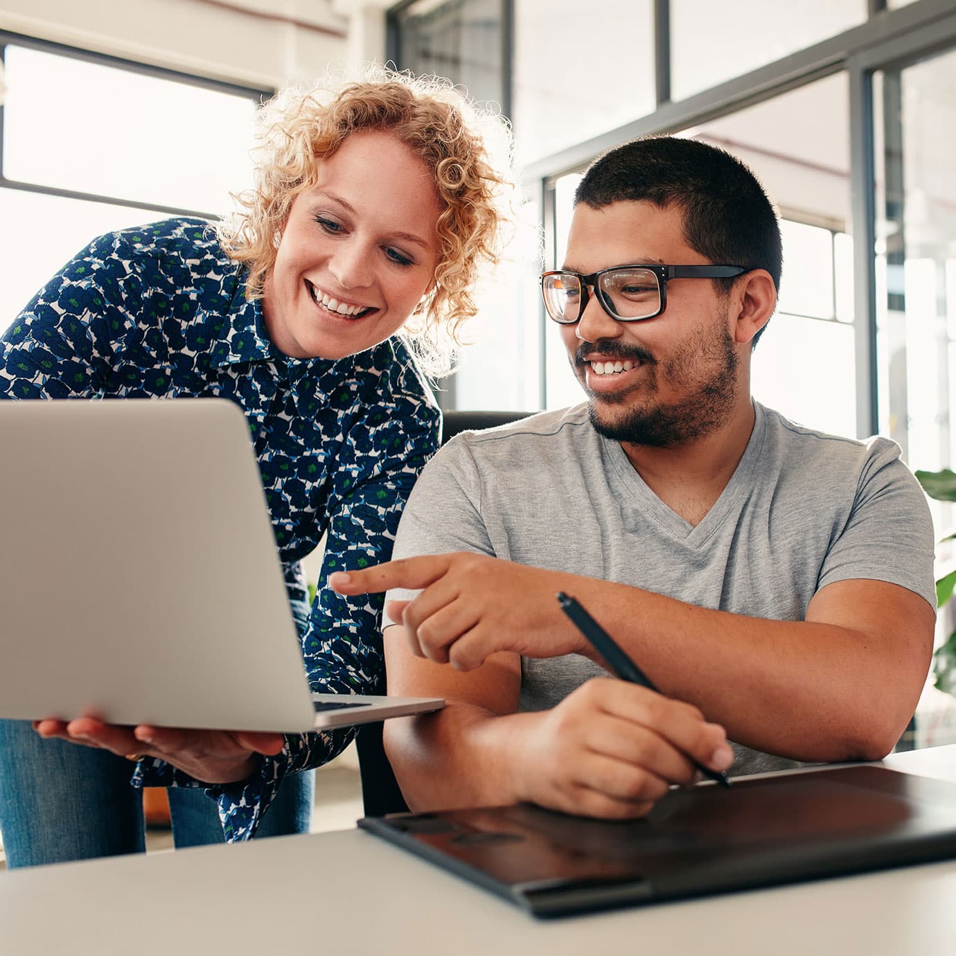 A man and woman gathering around a laptop