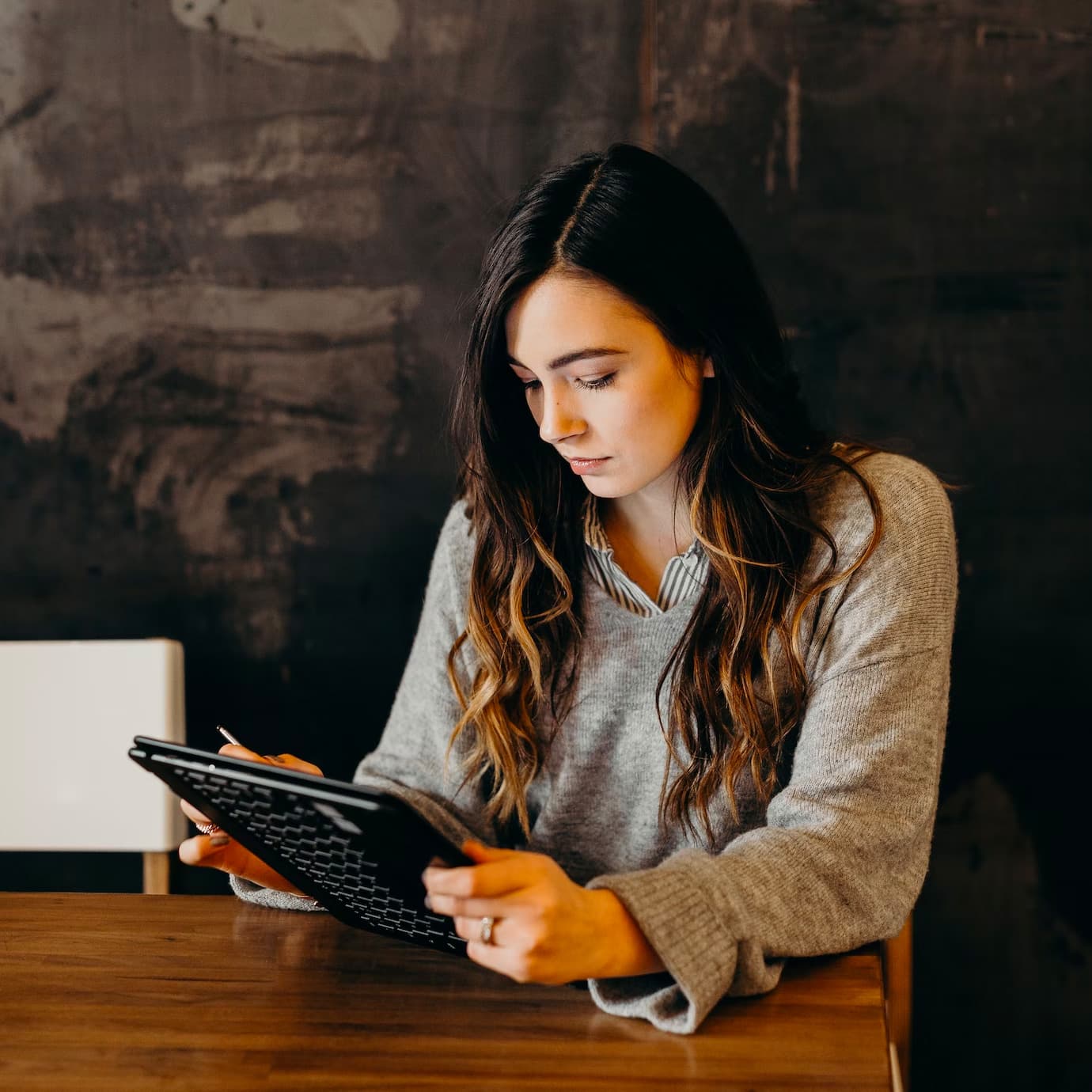 Woman holding a tablet and sitting at a table