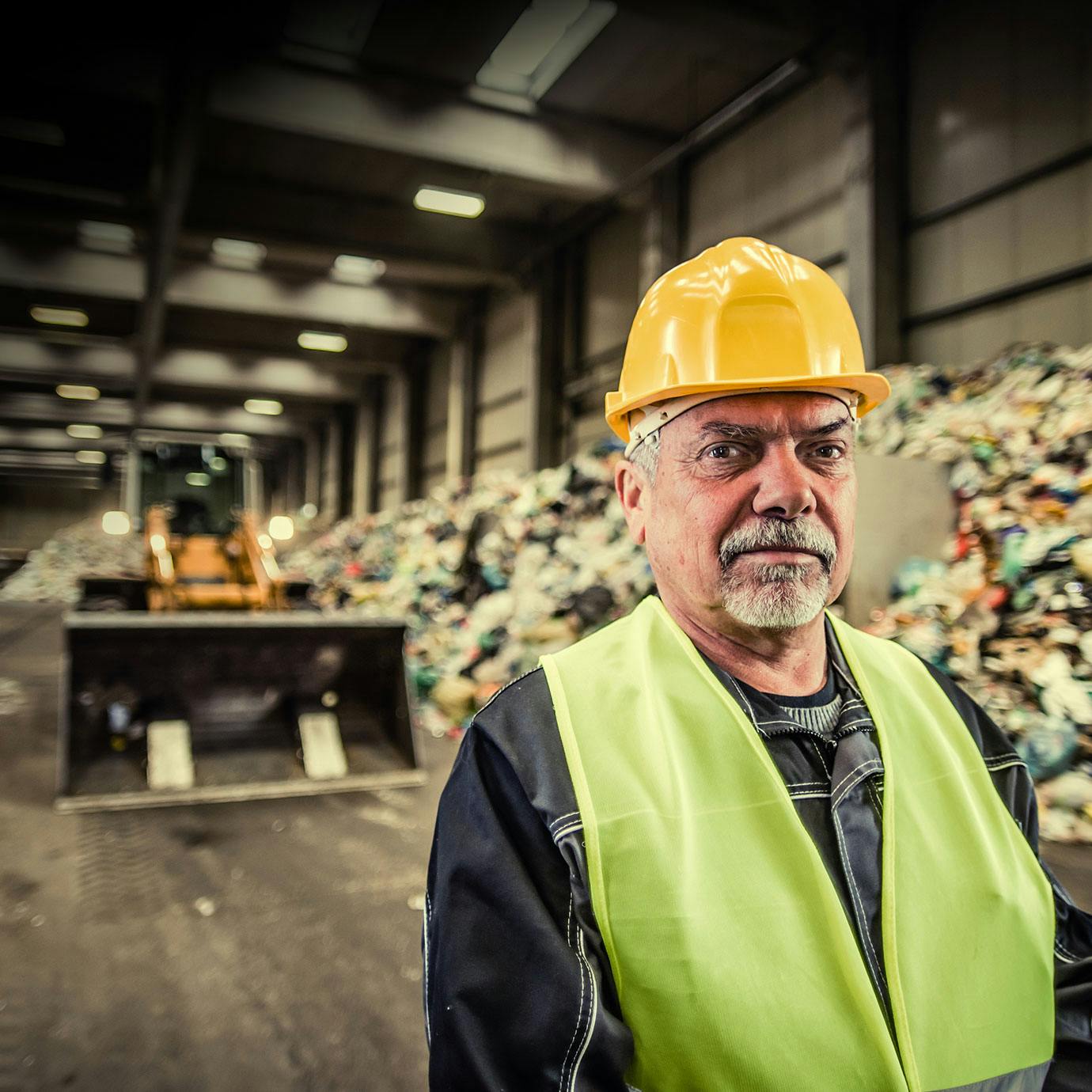Man standing in front of waste disposal area and bulldozer