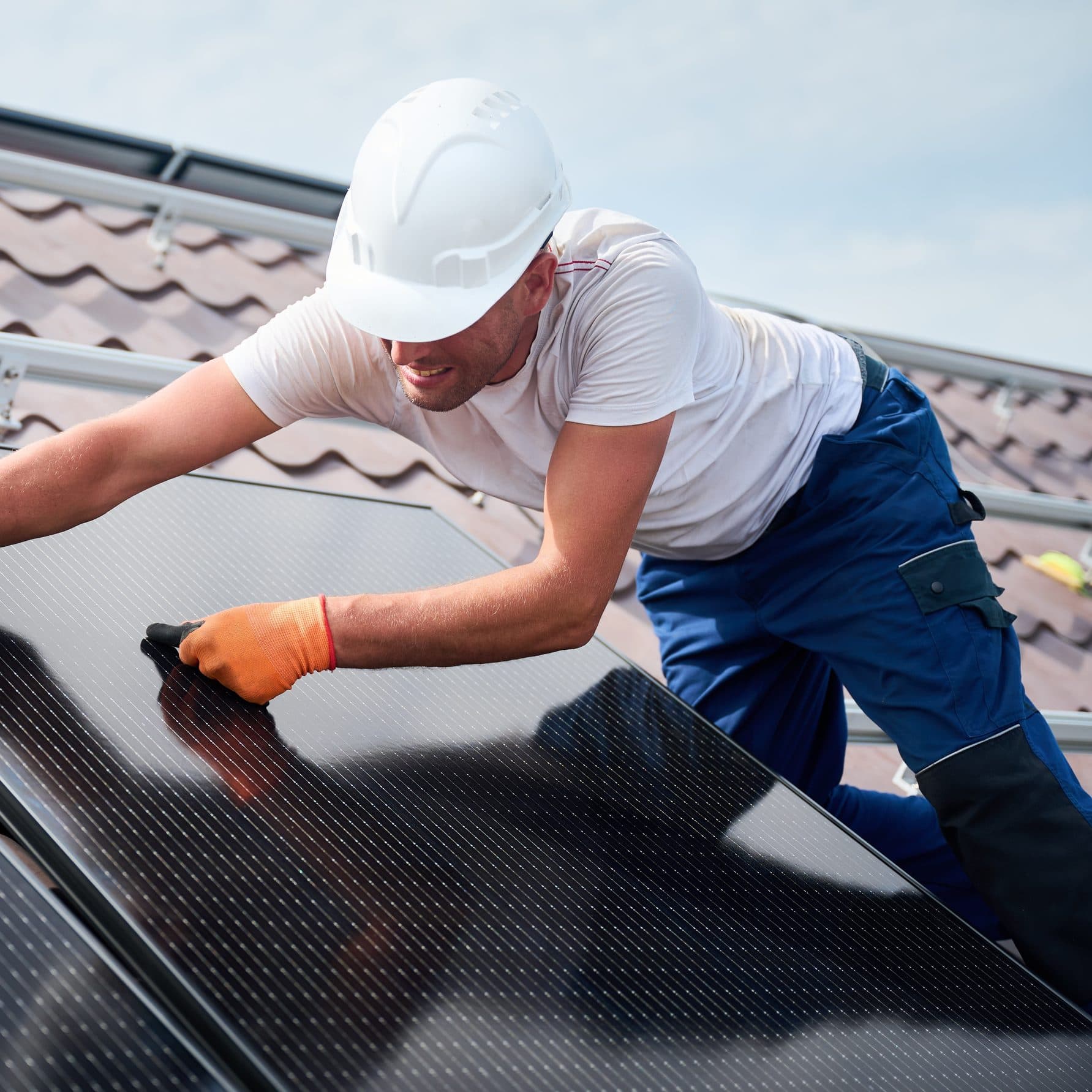 Installer fitting solar panels on a tiled house roof