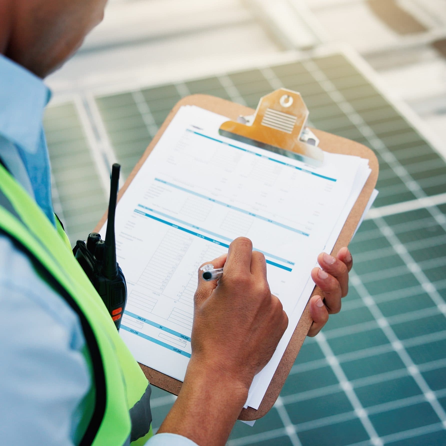 Surveyor completing a checklist beside solar panels