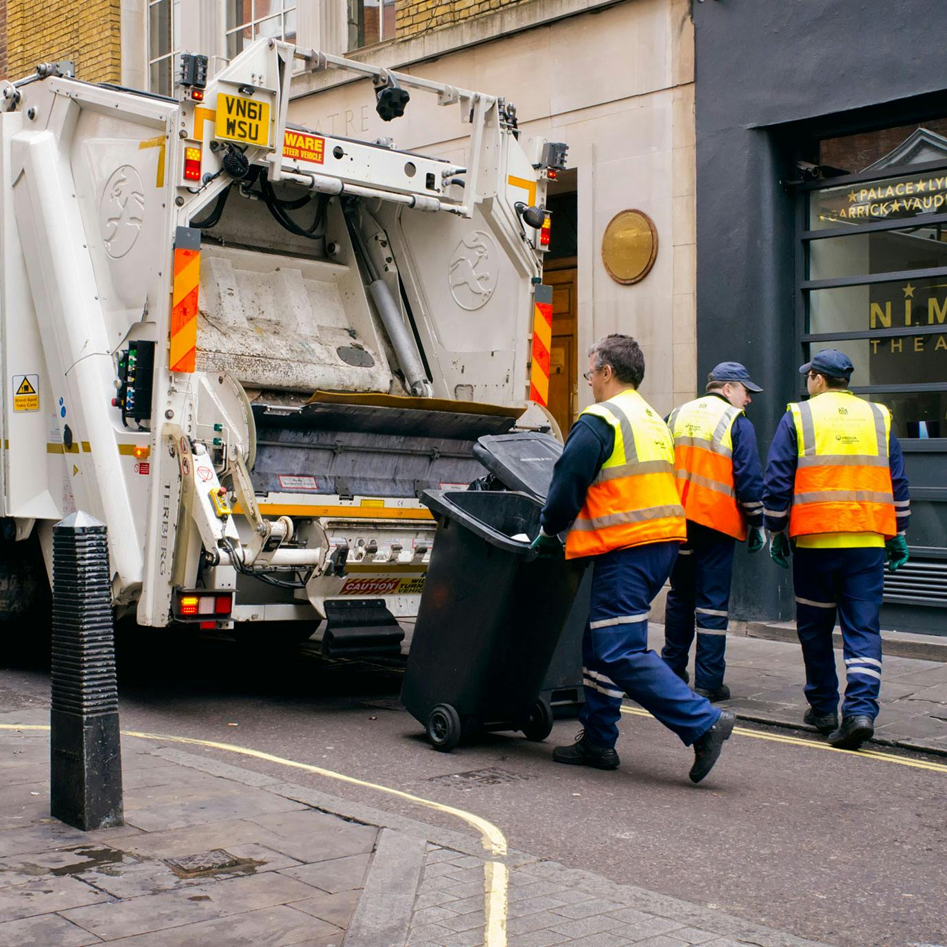 Refuse collectors disposing of bins in a lorry